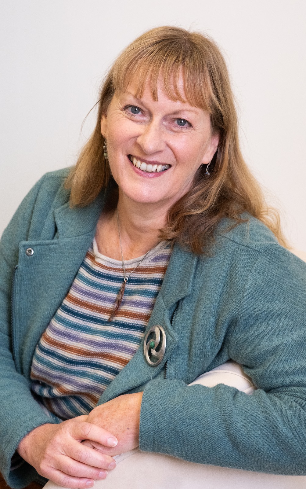 Gill smiling at the camera while leaning on the side of the sofa